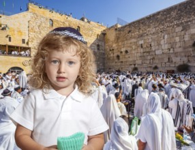 Llittle Jewish boy with side curls in yarmulke. Jews praying at the Western Wall. Ceremony at the