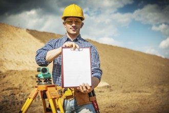 A young worker demonstrating clipboard on construction site