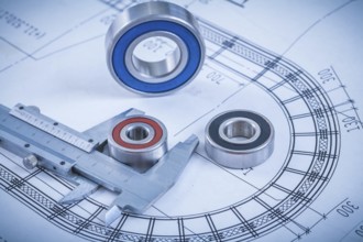 Metal roller bearings and trammel caliper on blueprint construction concept