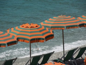 Close-up of orange-green parasols on the sandy seashore, Monte rosso, cinque terre, Italy, Europe