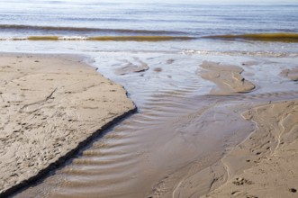 Gentle waves washing over the sandy beach creating small streams of water