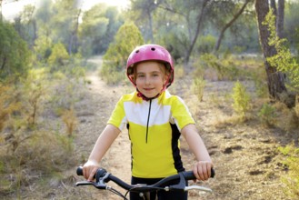 Kid girl biker in mountain bike MTB at mediterranean forest