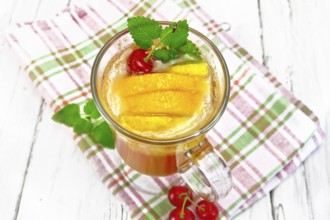 Lemonade in a wineglass with cherry, lemon and orange, mint on a napkin on a wooden plank