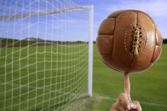 Football vintage ball in hand net soccer goal green grass background