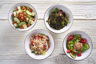Four salad mix bowls healthy food on white wood table