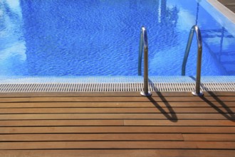 Blue swimming pool with teak wood flooring deck summer vacation concept