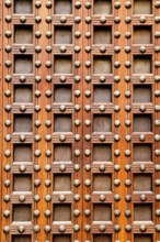 Ancient church castle wooden door with nails and little square shapes in spain