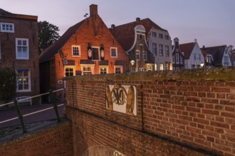 Brick houses and historic buildings illuminated in the evening twilight along a canal