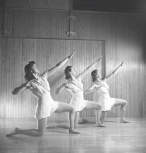 Gymnastics in the 1940s. Three young female gymnasts are practicing together and doing the same
