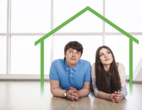 Happy young couple lying on the floor at home, dreaming