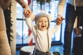 Funny little baby boy 1 year old learning walk home in winter in a decorated New Year house. Young