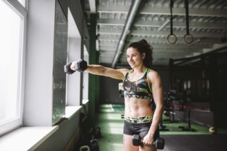 Attractive fit woman works out with dumbbells as a fitneß conceptual in gym