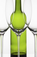 Three empty glasses of wine and green bottle on the white background
