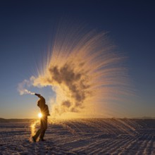 Woman throws hot water into the air that freezes into ice crystals, Mpemba effect, Unterallgäu,