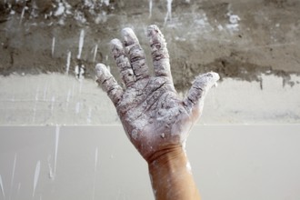 Astist plastering man hand with white dried cracked plaster texture in fingers