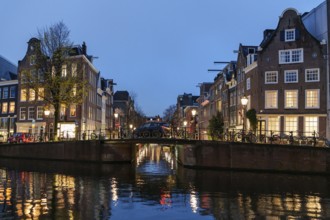 Reflection of lights on a quiet canal under an illuminated bridge, Amsterdam, Netherlands