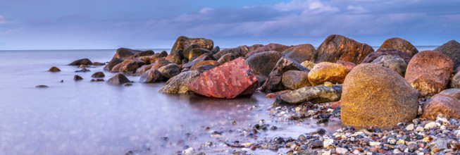 Panoramic photo of stones at the seaside with gentle water and beautiful details of nature long