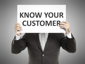 A business man holding a paper in front of his face with the text know your customer