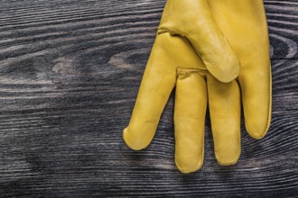 Leather yellow protective glove on vintage wooden board maintenance concept