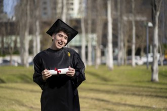 Young gay man recent graduated, dressed in cap and gown, showing off his degree celebrating