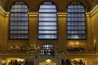 Large windows illuminate the station concourse, people move through the room, Manhattan, Brooklyn,