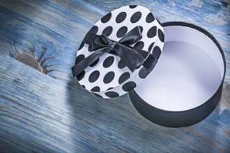 Round opened gift box with blue bow on wooden board holidays concept