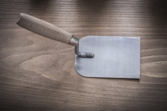 Metal bricklaying trowel on vintage wood board horizontal image