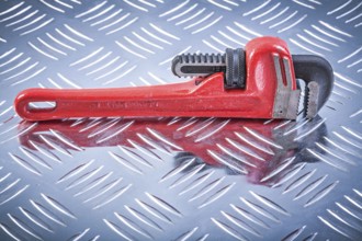 Monkey wrench on channeled metal background construction concept