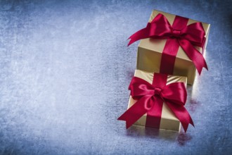 Boxed golden presents with red bow on scratched metallic background