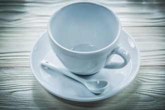 White ceramic cup saucer teaspoon on wooden board