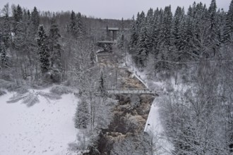 Aerial view of Myllykoski rapids on a cold winter day with snow covered ground and tree branches,