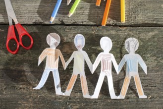 Paper made people figures. Painted white figures on wooden board