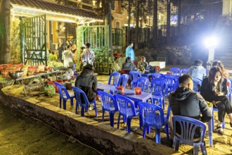 Empty blue chairs and tables under evening lights at a night market, restaurant in the streets of