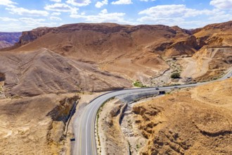 Asphalt highway meanders among the hills. Dead Sea mud has healing properties. Drone filming.