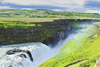 Grandiose Gullfoss in Iceland. In July raging water is shined with the bright morning sun. River