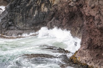 An image of an ocean wave on a red rock at New Zealand