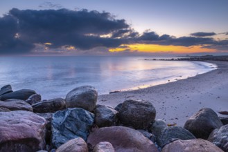 Atmospheric landscape at the seaside at sunrise with big stones in the foreground. Big stones at