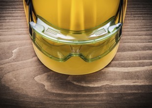 Safety spectacles and building helmet on wooden board construction concept