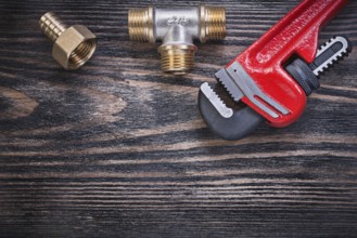 Monkey wrench brass equal tee hose nipple on wooden background plumbing concept