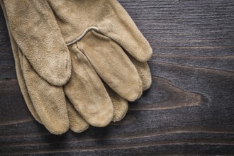 Pair of leather working gloves on vintage wooden board construction concept