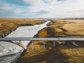 Bright blue river under the bridge trough Iceland mainland in autumn time on a cold day.