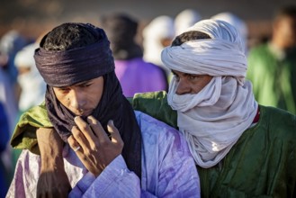 Two men in traditional dress and turbans, one puts his arm around the other, The traditional Tuareg