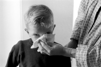 Boy in the 1950s. A mother holds a handkerchief over her sons nose as he blows his nose. Sweden