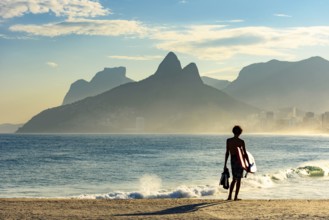 Young bodyboarder looking at the sea and Ipanema beach during a sunny afternoon