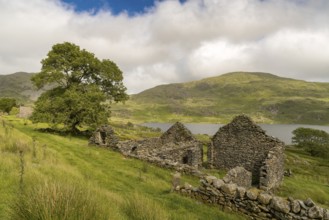 Grey clouds over Llyn Cwmystradllyn with a derelict ruin on the shore, near Penmorfa, Gwynedd,