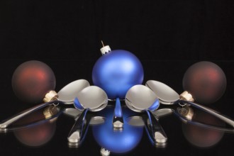 Blue Christmas decoration and five spoons on a black glass desk
