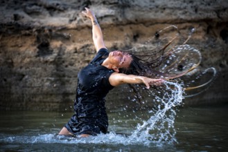 Middle-aged woman dancing and throwing water in the air, Maioris beach, llucmajor, Majorca,