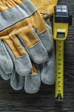 Set of tape measure protective gloves on wooden board