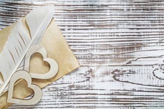 Old paper sheet plume wooden hearts on vintage wood board celebrations concept