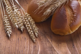 Bread with wheat ears on old wooden board